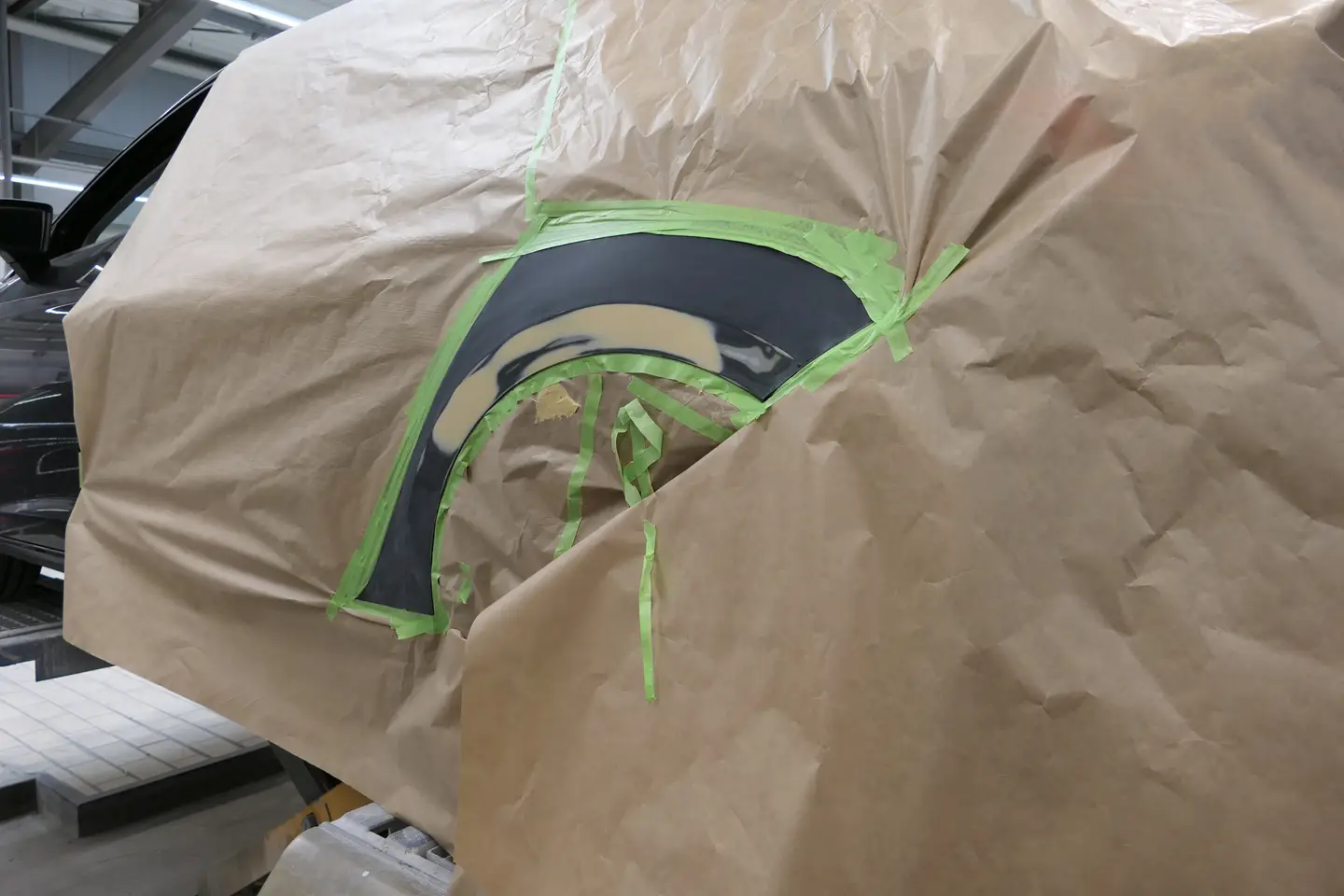 Impressionen Mit naturfarbenem Papier abgeklebtes Kundenfahrzeug zur weiteren Vorbereitung des hinteren Radlauf